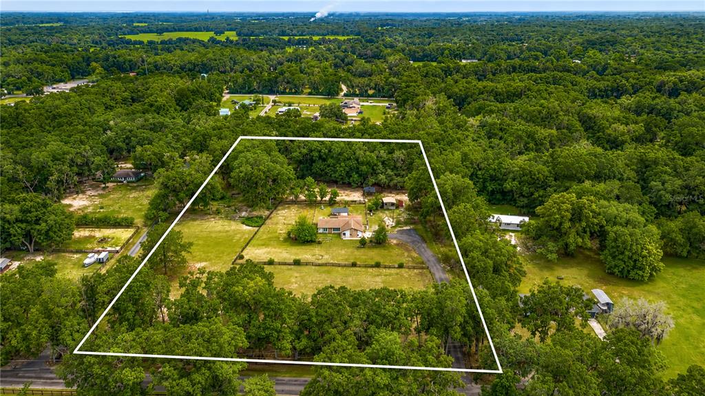 An aerial view shows a house situated on a large, tree-lined, fenced-in grassy lot — 2735 NE 127TH PLACE, ANTHONY, FL