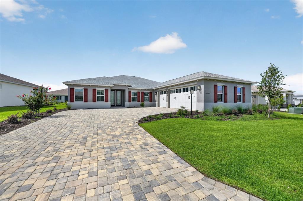 A single-story house with a paved driveway, a three-car garage, and red window shutters — 10202 SW 84TH STREET ROAD, OCALA, FL