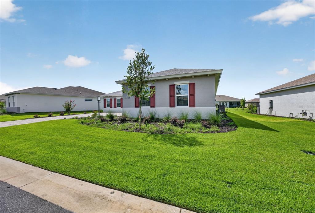 A single-story house with gray siding, red shutters, and a landscaped front yard — 10202 SW 84TH STREET ROAD, OCALA, FL
