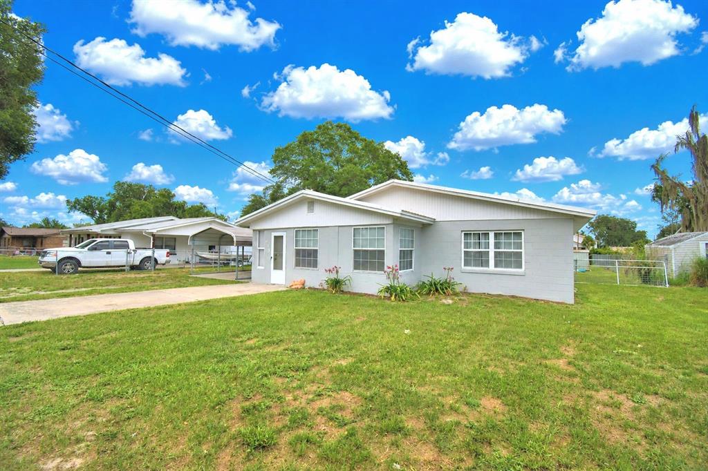 A single-story gray house with a white roof and a concrete driveway under blue skies — 906 N 9TH AVENUE, WAUCHULA, FL