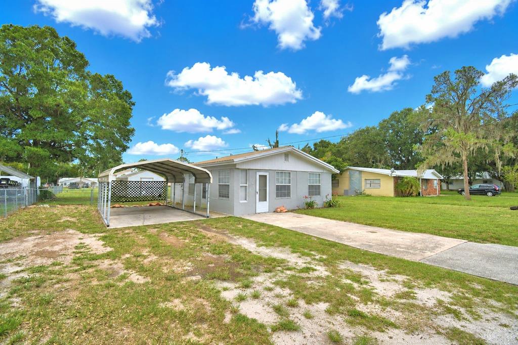 A gray single-story house features a metal carport and a concrete driveway on a grassy lot — 906 N 9TH AVENUE, WAUCHULA, FL