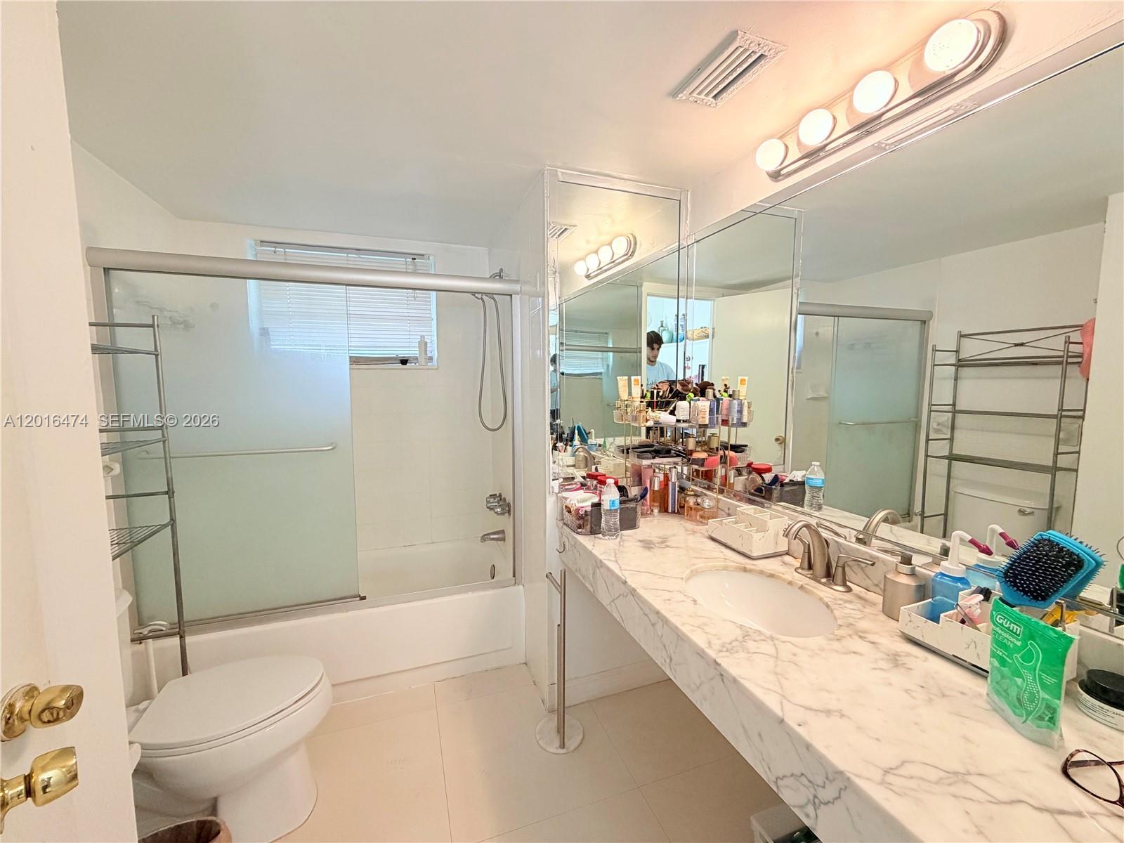 A bathroom features a marble vanity, a shower-tub combination with sliding doors, and a toilet — 1680 NE 191st St # 2, Miami FL 33179, MIAMI, FL