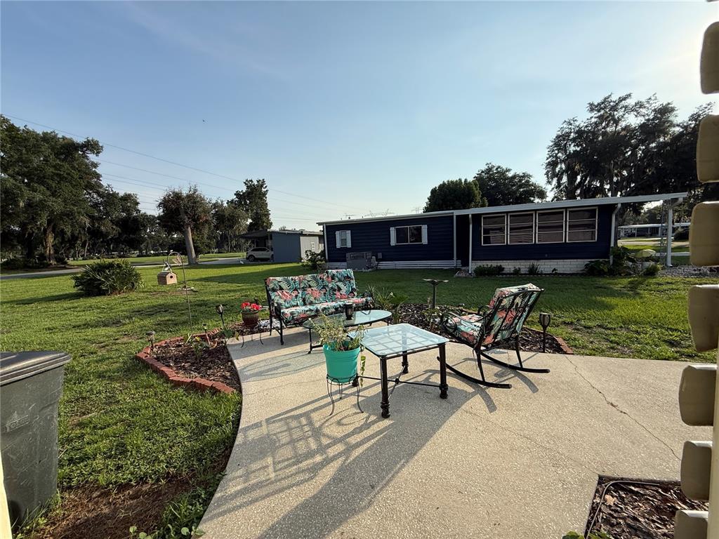 A patio with outdoor furniture sits on a lawn in front of a blue house — 48 S BOBWHITE ROAD, WILDWOOD, FL