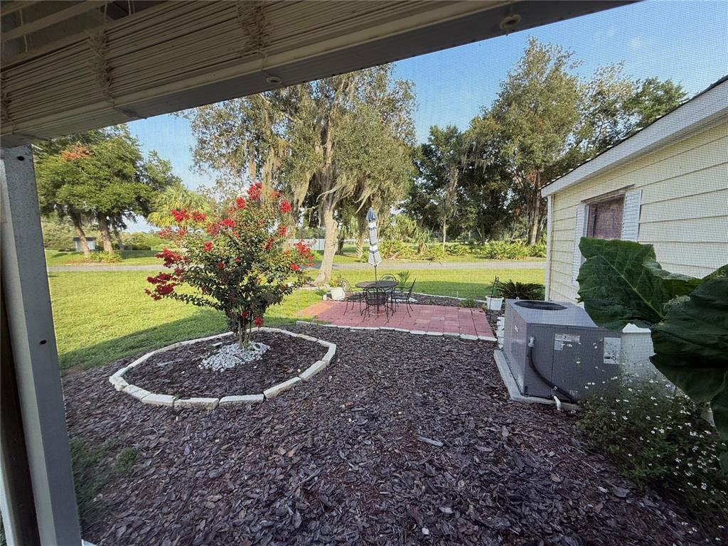A backyard patio features a brick seating area, a crepe myrtle tree, and landscaping mulch — 48 S BOBWHITE ROAD, WILDWOOD, FL