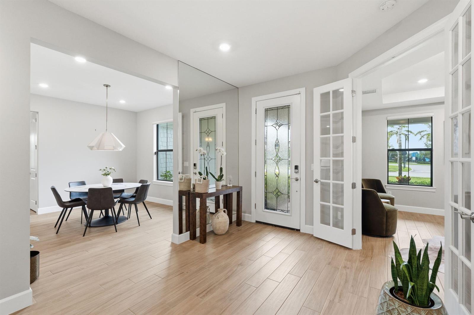 A bright entryway features light wood-look tile floors, a mirrored wall, and a dining area — 208 Sonoma Isles Circle, Jupiter FL 33478, JUPITER, FL