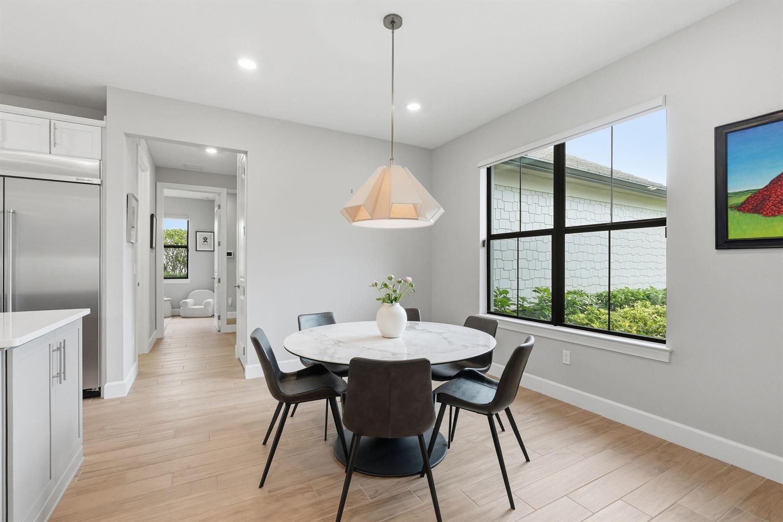 A dining area features a round marble table, four chairs, and a modern pendant light — 208 Sonoma Isles Circle, Jupiter FL 33478, JUPITER, FL