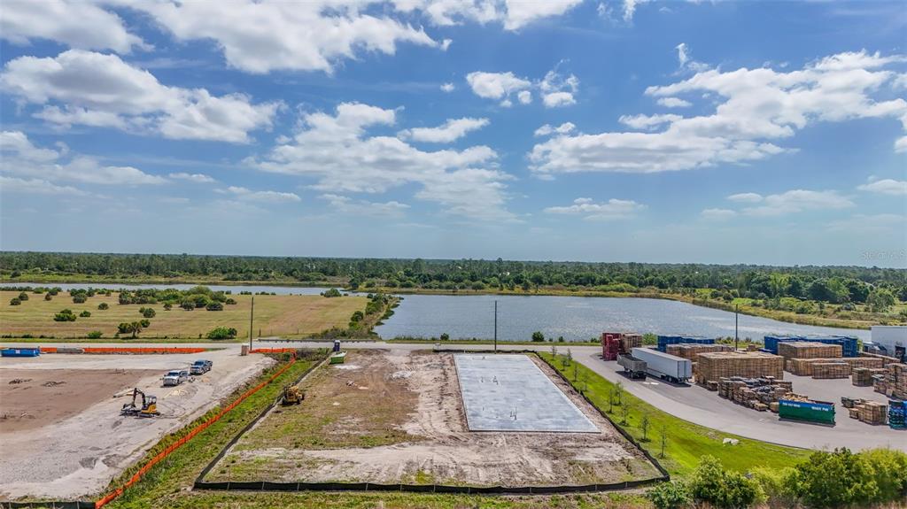 An aerial view shows a vacant lot with a concrete foundation slab near a lake — 8429 NORTHUP DRIVE UNIT 4, PUNTA GORDA, FL