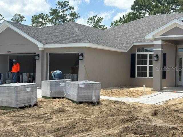 A single-story house under construction features a garage, gray exterior walls, and palletized pavers — 6878 SW 179TH AVENUE ROAD, DUNNELLON, FL