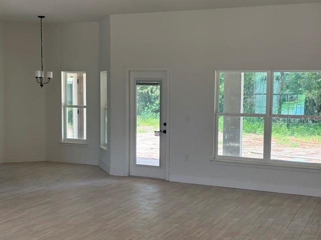 A bright room with light-colored tile flooring, a chandelier, a glass door, and large windows — 6878 SW 179TH AVENUE ROAD, DUNNELLON, FL