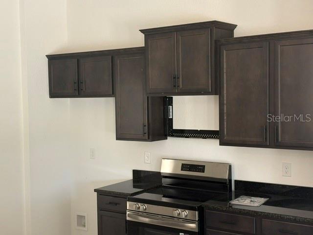 A kitchen features dark wood cabinets, black countertops, and a stainless steel electric range — 6878 SW 179TH AVENUE ROAD, DUNNELLON, FL