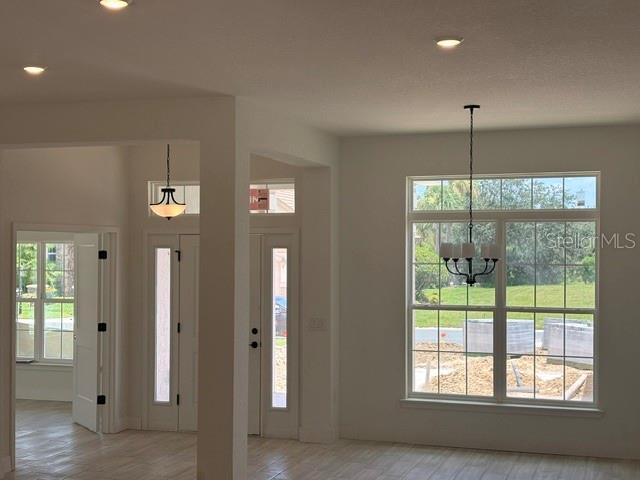 An interior view of a room with light-colored flooring, white walls, and two hanging chandeliers — 6878 SW 179TH AVENUE ROAD, DUNNELLON, FL