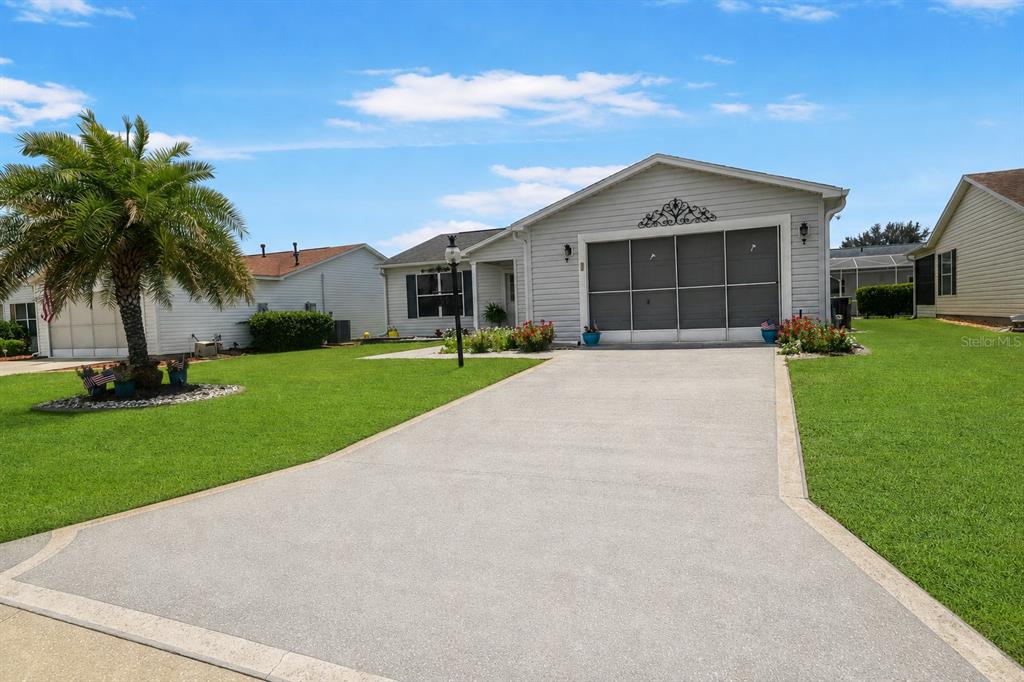 A single-story house with light gray siding, a screen-enclosed garage, and a palm tree — 3448 JACONA PLACE, THE VILLAGES, FL