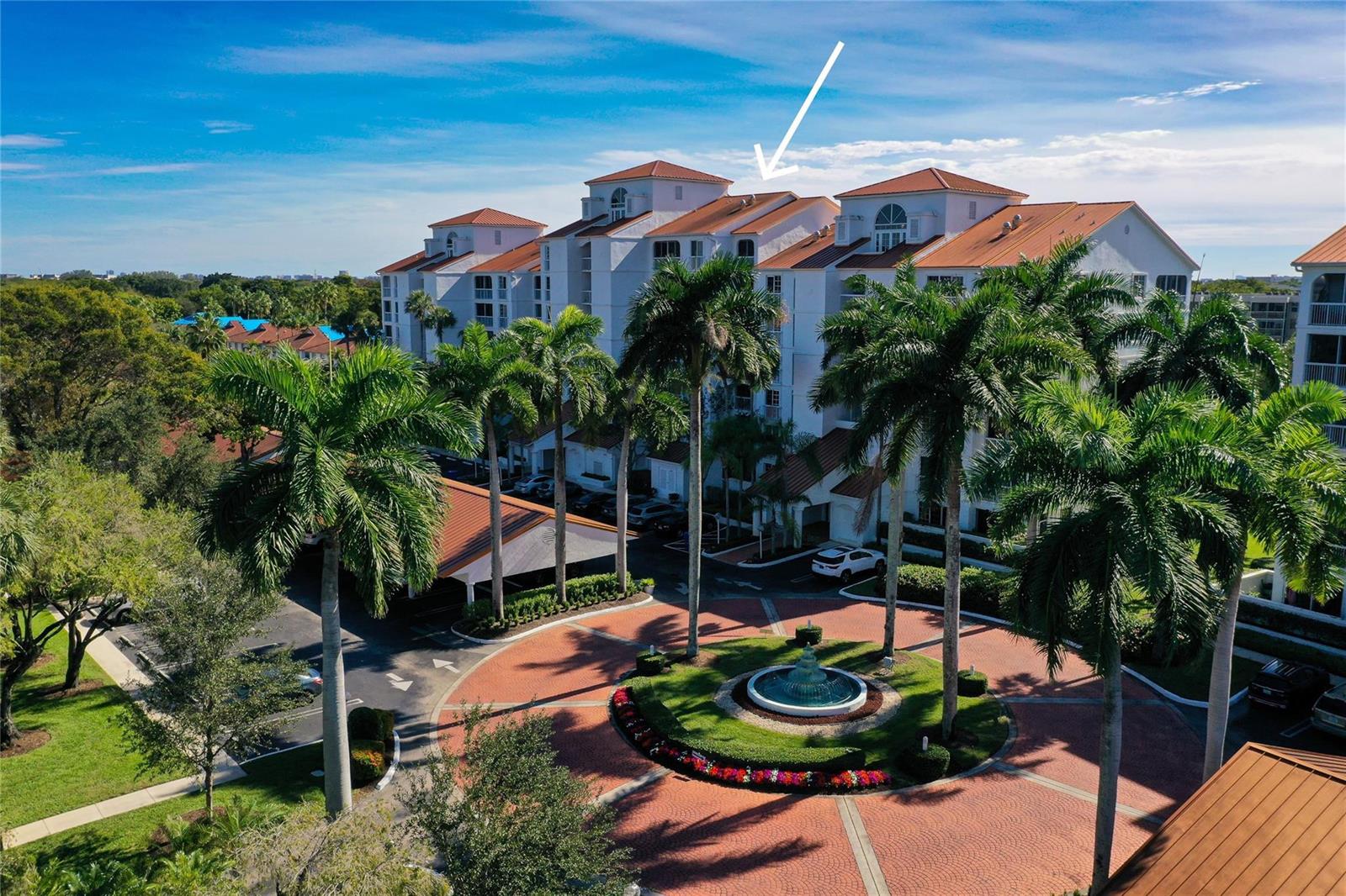 An aerial view of a multi-story apartment building with a fountain and palm trees — 4108 W Palm Aire Drive # 083b, Pompano Beach FL 33069, POMPANO BEACH, FL