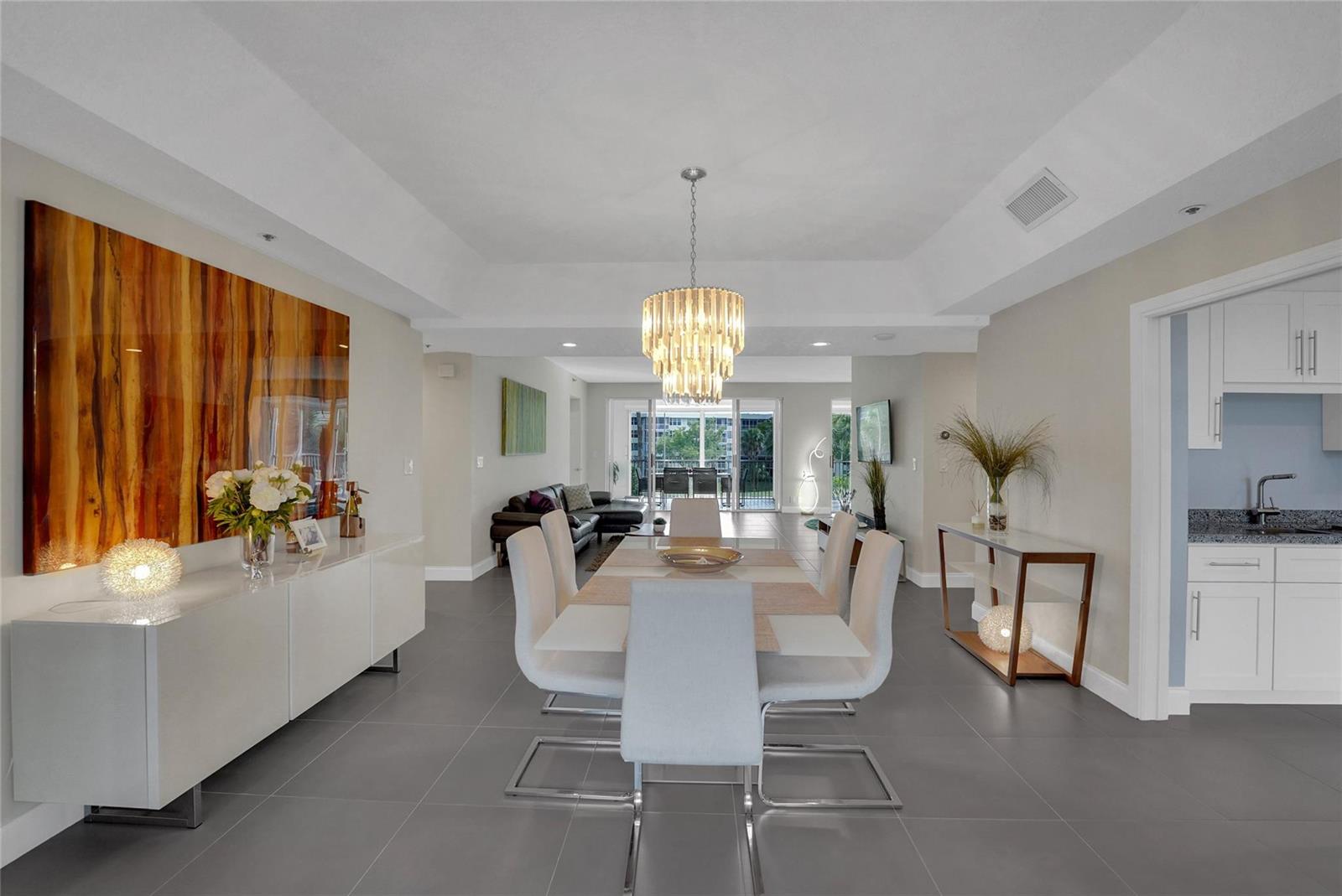 A dining room with a crystal chandelier, white chairs, and gray tile flooring — 4108 W Palm Aire Drive # 083b, Pompano Beach FL 33069, POMPANO BEACH, FL