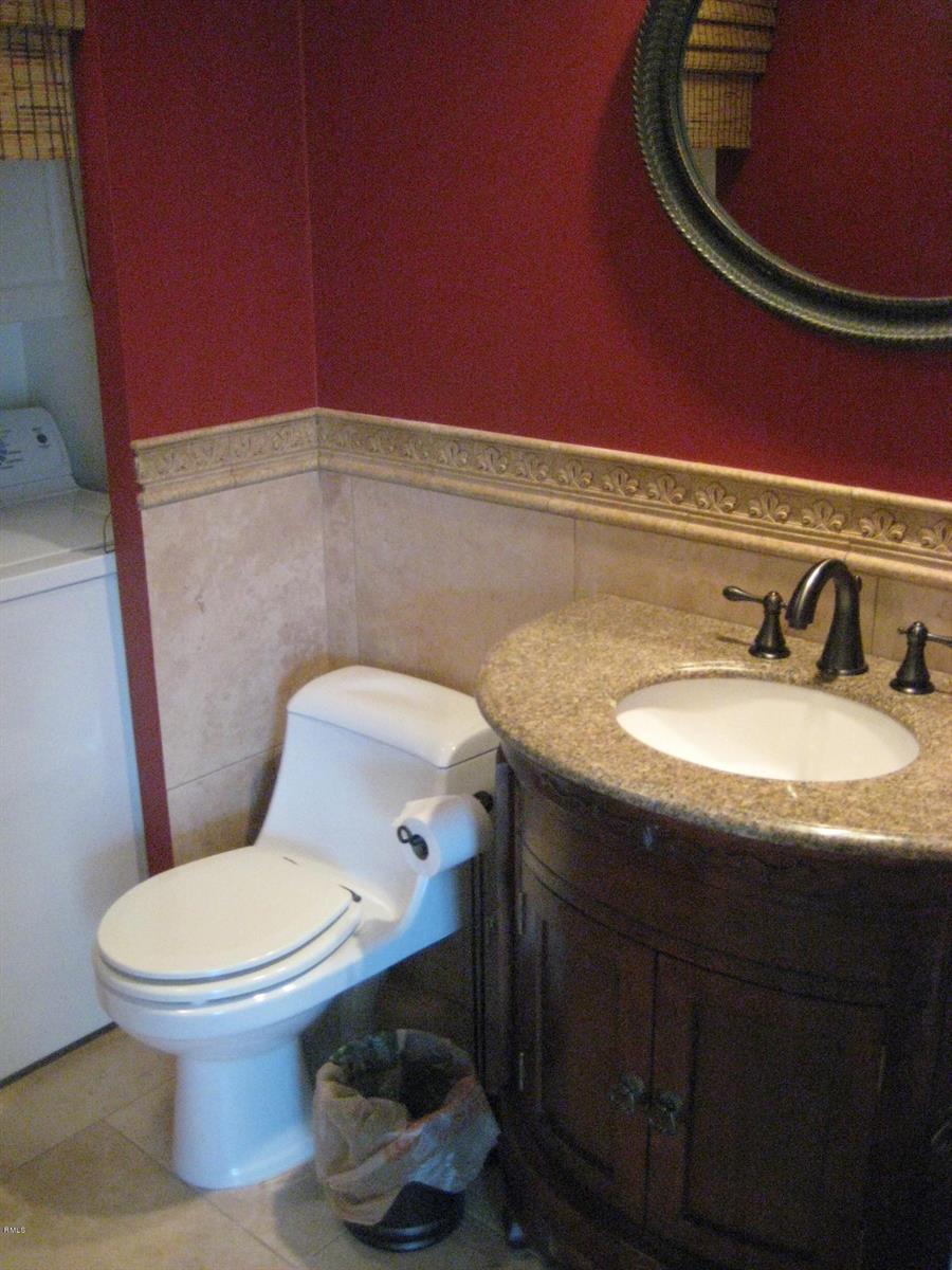 A bathroom features a toilet, a vanity with a stone countertop, and red walls — 3900 SE County Line Road # 24d, Tequesta FL 33469, TEQUESTA, FL