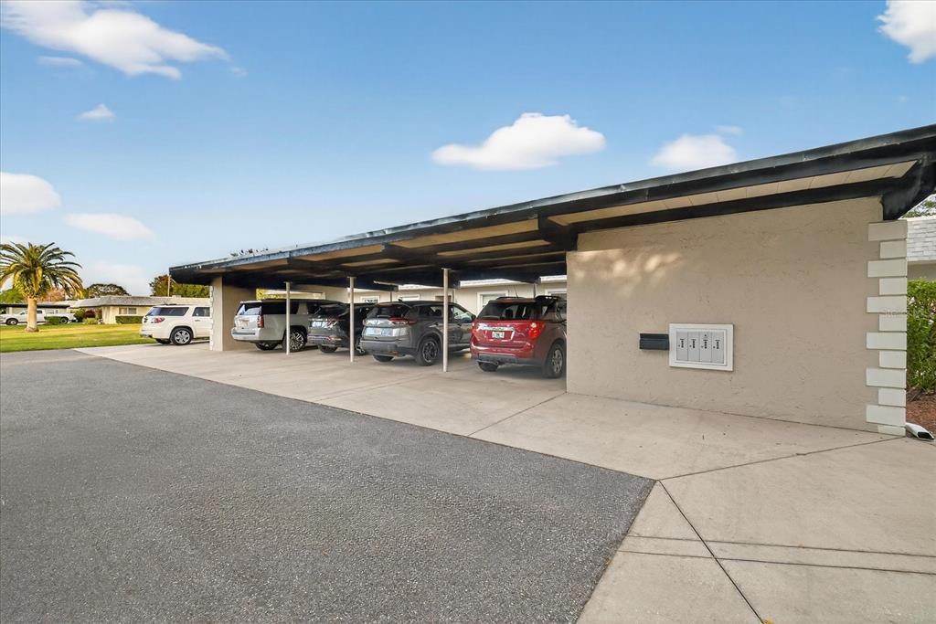 A covered carport with multiple parked vehicles sits beside a building with exterior mailboxes — 3230 TEESIDE DRIVE, NEW PORT RICHEY, FL