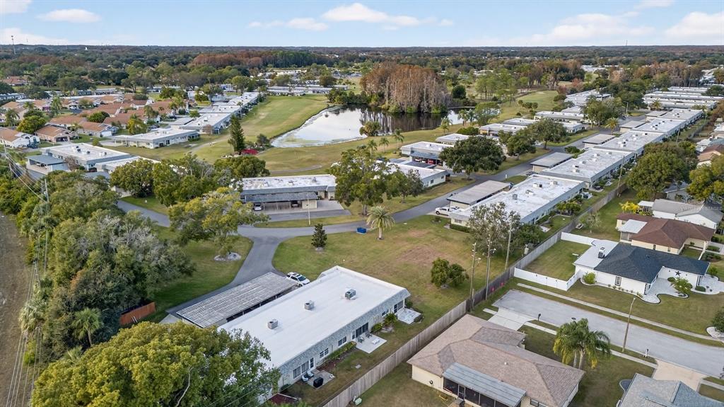 An aerial view shows a residential community with flat-roofed buildings, a pond, and green spaces — 3230 TEESIDE DRIVE, NEW PORT RICHEY, FL