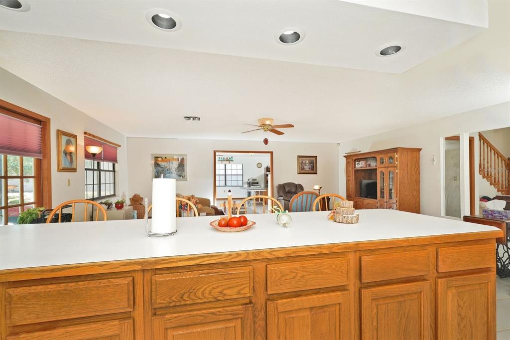 A kitchen island with a white countertop faces a living area with wood cabinetry — 2080 NEWFOUND HARBOR DRIVE, MERRITT ISLAND, FL