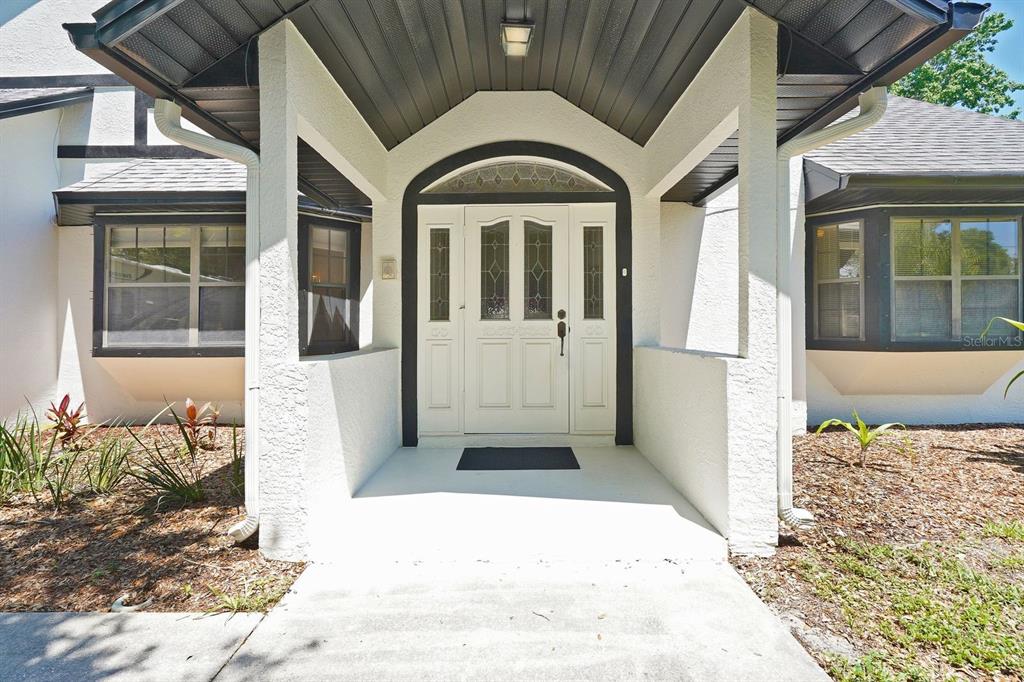 The exterior of a house features a covered entryway with a white front door — 2080 NEWFOUND HARBOR DRIVE, MERRITT ISLAND, FL