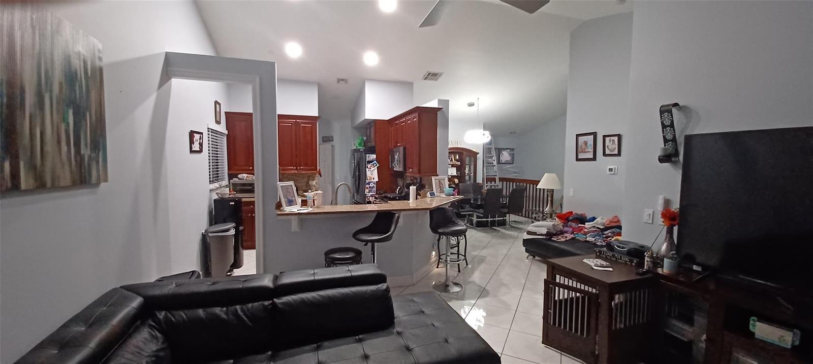 A living room with a black leather sofa, breakfast bar, and kitchen in the background — 20 Via De Casas Sur # 204, Boynton Beach FL 33426, BOYNTON BEACH, FL