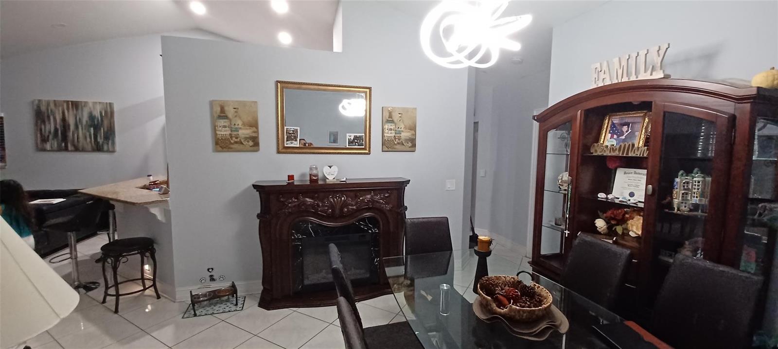 A dining room features a fireplace, a glass table, and a dark wood display cabinet — 20 Via De Casas Sur # 204, Boynton Beach FL 33426, BOYNTON BEACH, FL