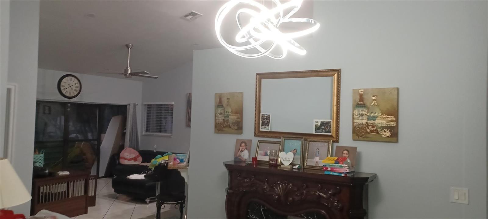 A living room features a fireplace, a large mirror, wall art, and a modern light fixture — 20 Via De Casas Sur # 204, Boynton Beach FL 33426, BOYNTON BEACH, FL