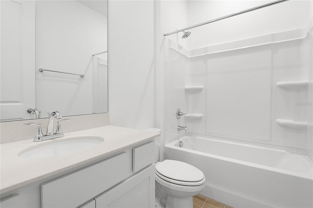 A bathroom features a white vanity with a sink, a toilet, and a tub-shower combo — 5220 BEE BALM STREET, LAKE HAMILTON, FL