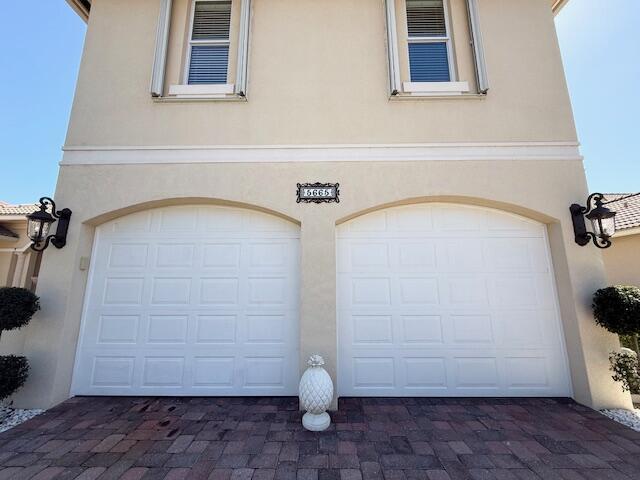 The exterior of a two-story house features two white garage doors and a stone driveway — 5665 61st Place, Vero Beach FL 32967, VERO BEACH, FL