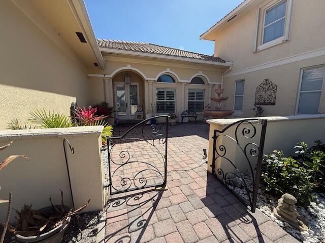 A paved courtyard features a decorative fountain, wrought iron gates, and arched windows — 5665 61st Place, Vero Beach FL 32967, VERO BEACH, FL