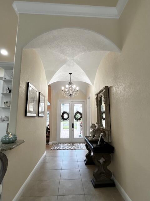 A foyer features a vaulted ceiling, a crystal chandelier, and double glass entry doors — 5665 61st Place, Vero Beach FL 32967, VERO BEACH, FL