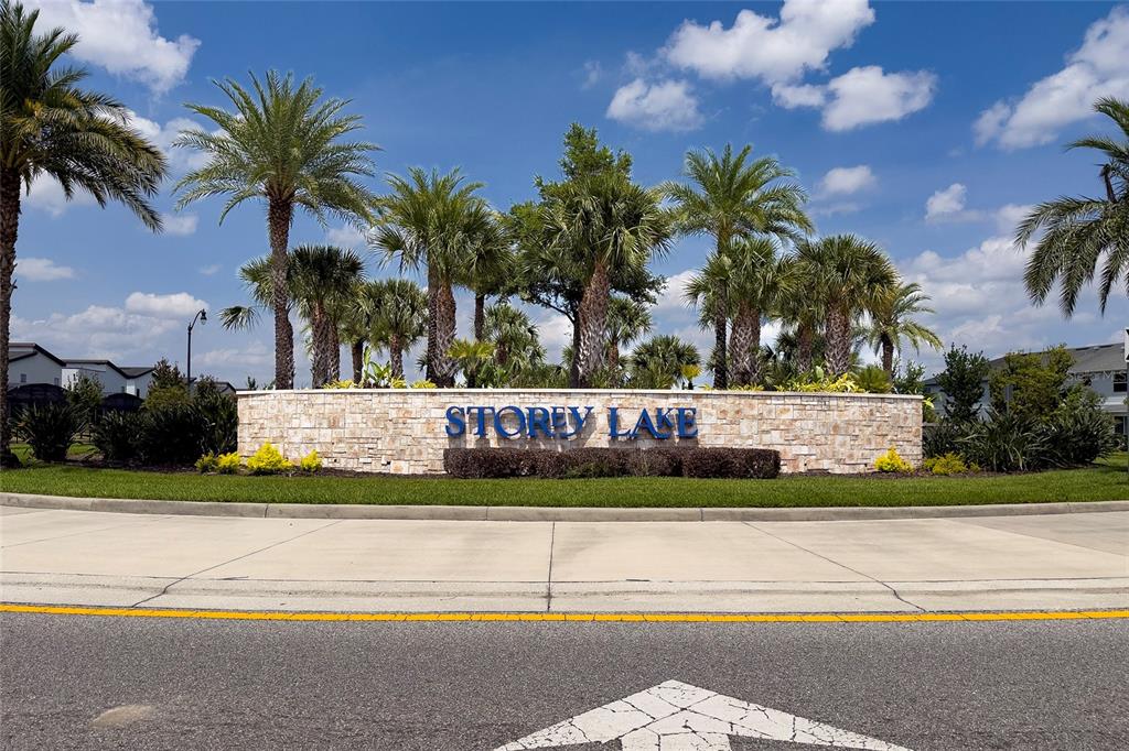 A stone monument sign reading Storey Lake sits behind a road with palm trees — 4756 TRIBUTE TRAIL, KISSIMMEE, FL