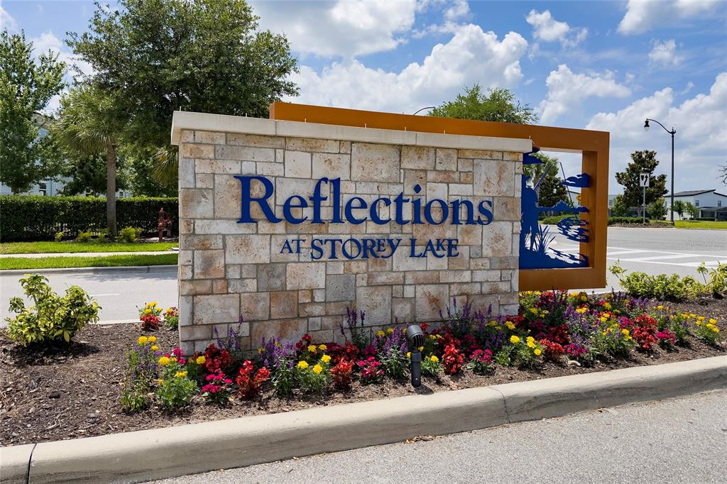 A stone monument sign for Reflections at Storey Lake sits in a landscaped garden bed — 4756 TRIBUTE TRAIL, KISSIMMEE, FL