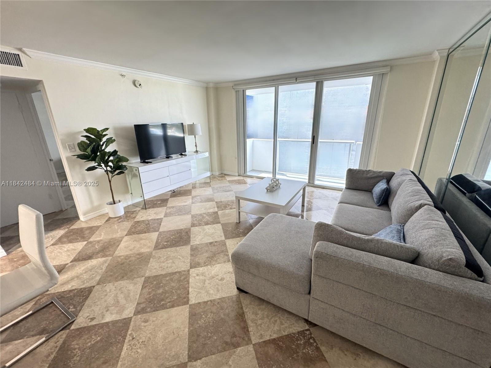 A living room features a gray sectional sofa, white media console, and checkered tile flooring — 9195 Collins Ave # 912, Surfside FL 33154, SURFSIDE, FL