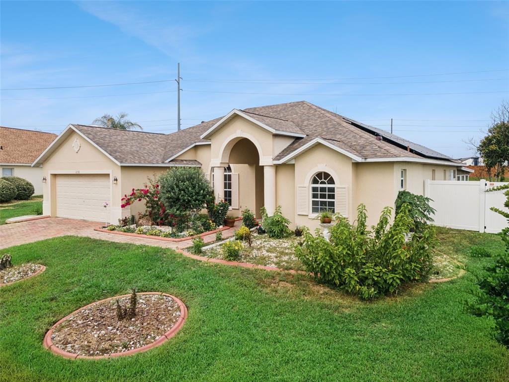 A single-story house with a beige stucco exterior, a two-car garage, and a landscaped yard — 236 DOLCETTO DRIVE, DAVENPORT, FL