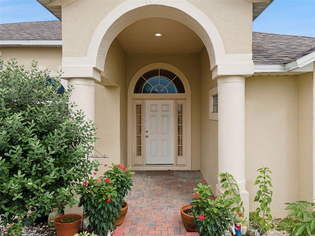 The front entrance features a white door with a transom window under a covered archway — 236 DOLCETTO DRIVE, DAVENPORT, FL