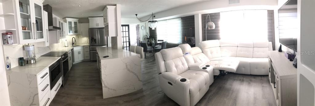 A panoramic view of an open-concept kitchen and living room with white cabinetry and furniture — 3315 58TH AVENUE S UNIT 416, ST PETERSBURG, FL