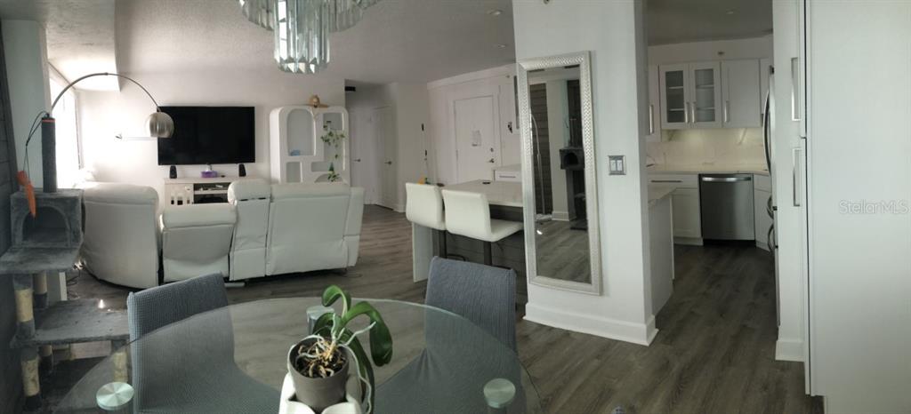 A living room and kitchen area with white furniture, wood flooring, and a dining table — 3315 58TH AVENUE S UNIT 416, ST PETERSBURG, FL