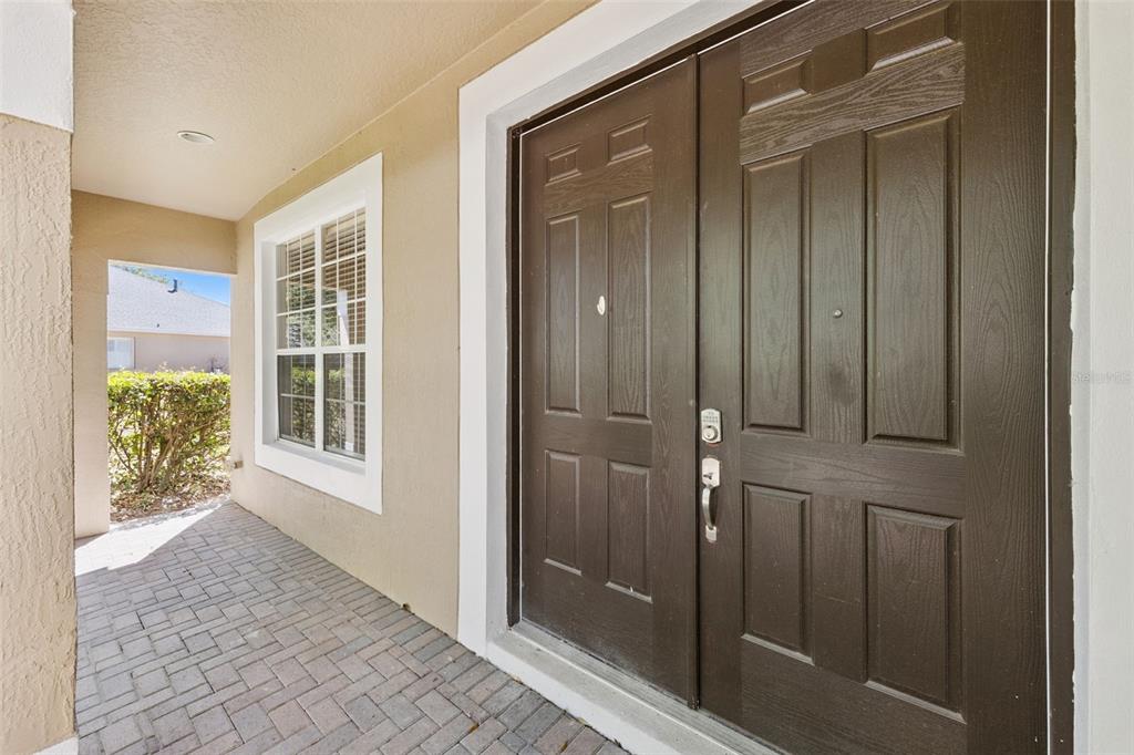 A dark brown double front door sits on a brick porch next to a window — 2692 CEDAR KNOLL DRIVE, APOPKA, FL