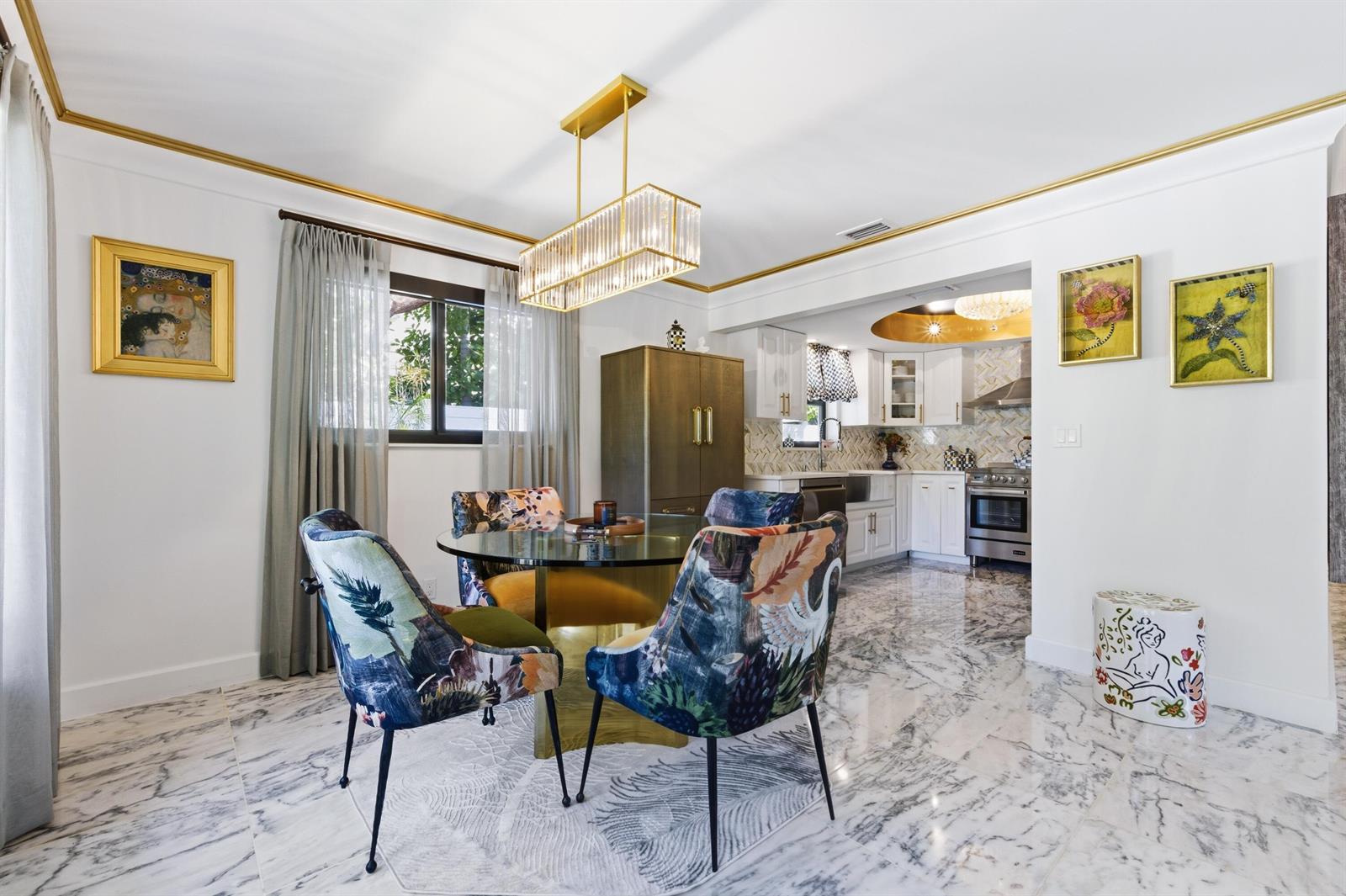 A dining area with a glass table, patterned chairs, and marble floors opens to a kitchen — 702 S Atlantic Drive, Lantana FL 33462, LANTANA, FL