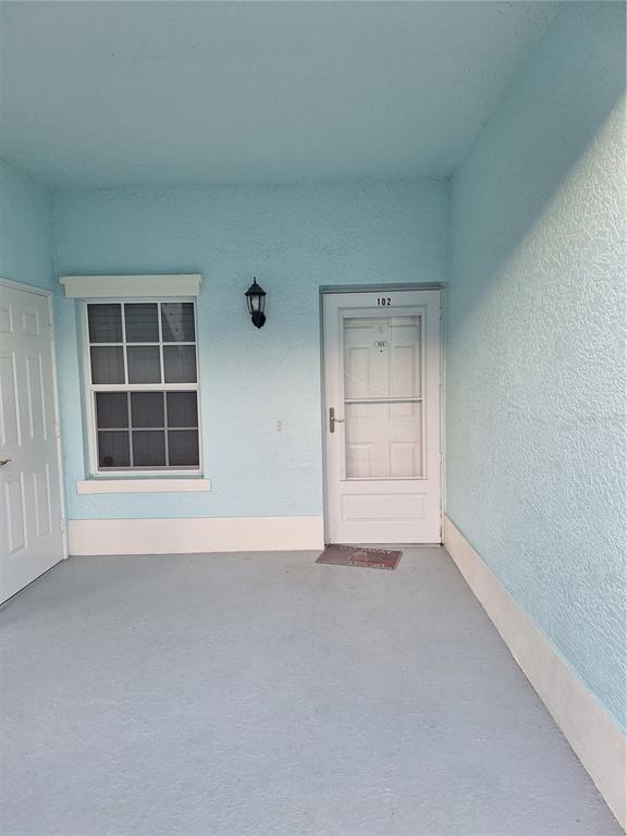 A light blue exterior entryway features a white door, a window, and a wall lamp — 5748 SABAL TRACE DRIVE UNIT 102, NORTH PORT, FL