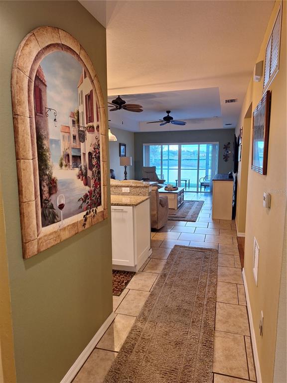 A hallway with tile flooring leads into an open-concept living area with a water view — 5748 SABAL TRACE DRIVE UNIT 102, NORTH PORT, FL