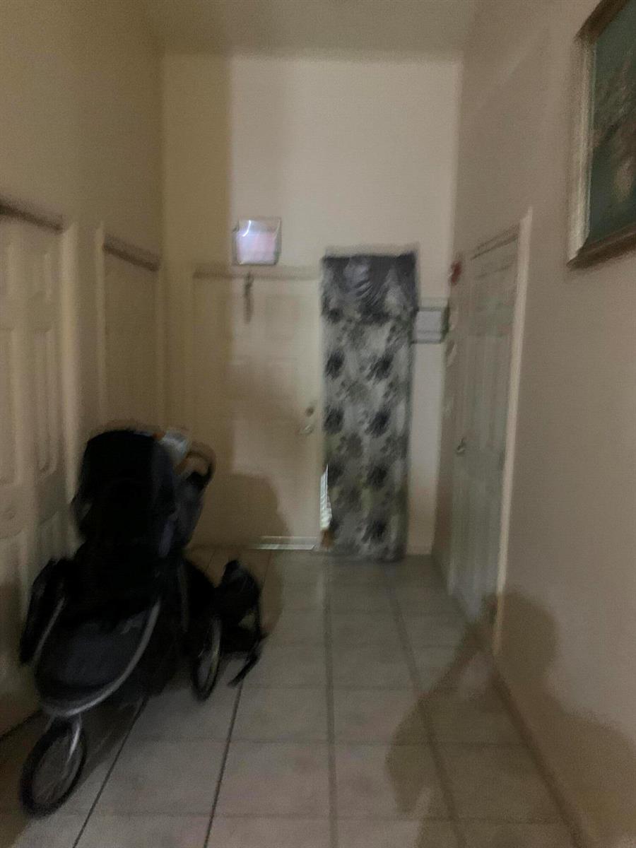 A tiled hallway features a stroller, several closed doors, and a patterned curtain over a doorway — 198 Sparrow Drive, Royal Palm Beach FL 33411, ROYAL PALM BEACH, FL