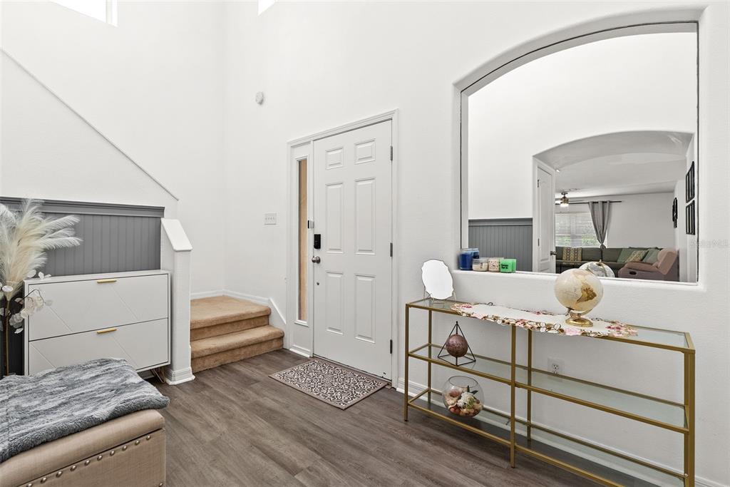 A bright entryway features wood-look flooring, a white front door, and a gold console table — 12607 CHENWOOD AVENUE, HUDSON, FL