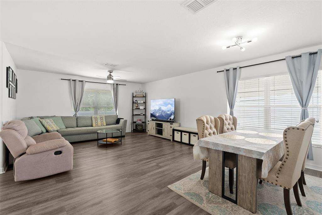 A living and dining room with wood-look flooring, a grey sofa, and a dining set — 12607 CHENWOOD AVENUE, HUDSON, FL