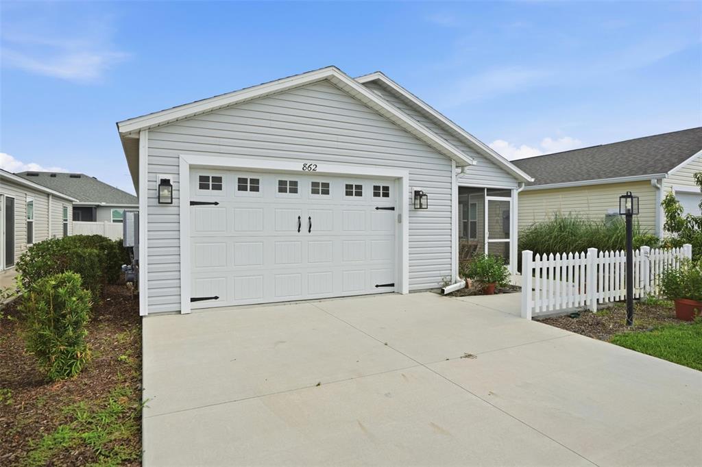 A light gray house with a white garage door and a small white picket fence — 862 SPRING AVENUE, THE VILLAGES, FL