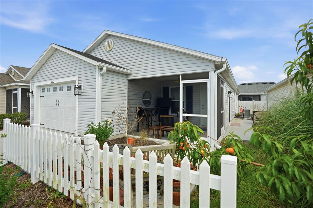 A light gray vinyl-sided house features a white picket fence and a screened-in patio — 862 SPRING AVENUE, THE VILLAGES, FL
