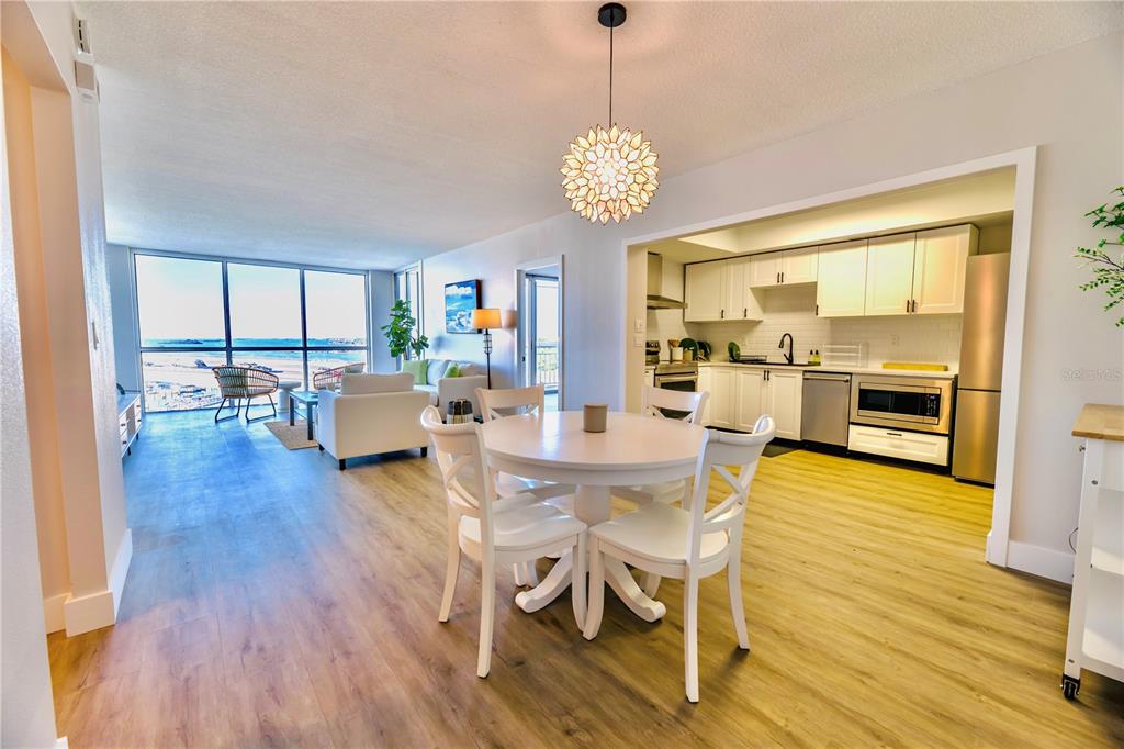 A dining area with a round table and pendant light opens to a kitchen and living room — 100 PIERCE STREET UNIT 1102, CLEARWATER, FL