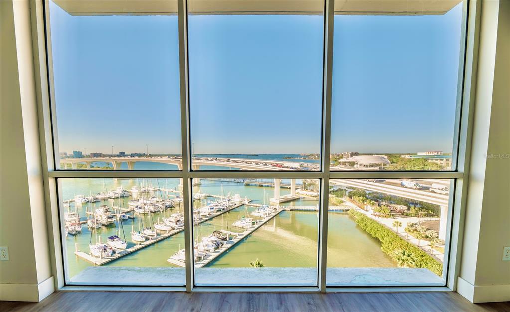 A room with floor-to-ceiling windows overlooking a marina and a bridge — 100 PIERCE STREET UNIT 1102, CLEARWATER, FL
