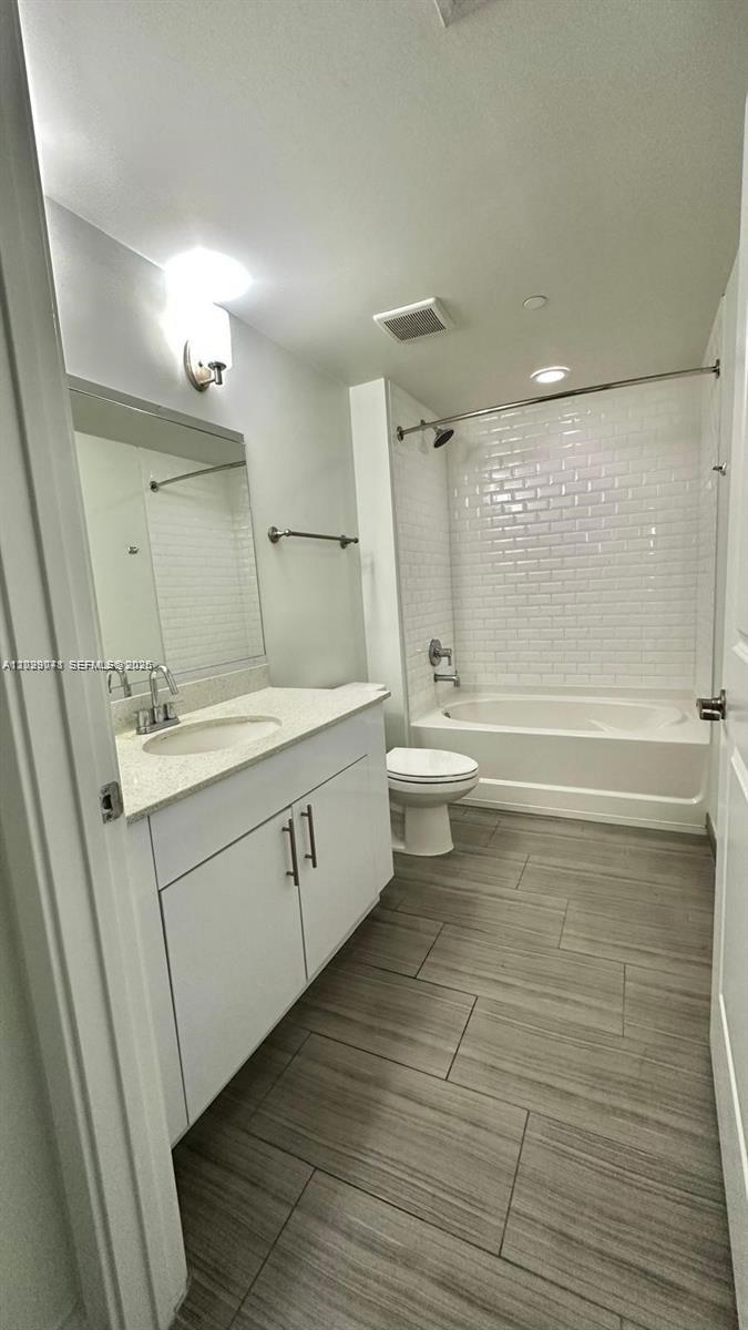 A bathroom features a white vanity, a toilet, and a bathtub with white subway tile — 1776 Polk St # 1403, Hollywood FL 33020, HOLLYWOOD, FL