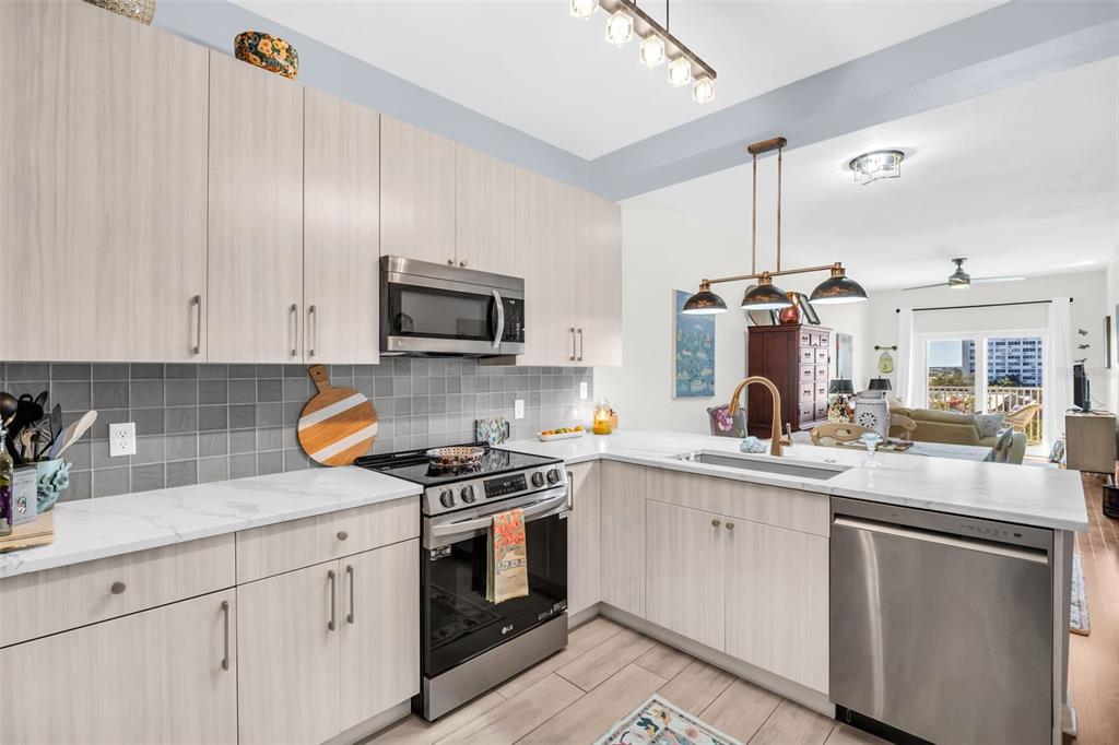 A modern kitchen features light wood cabinets, stainless steel appliances, and a white marble countertop — 316 8TH STREET S UNIT 402, ST PETERSBURG, FL